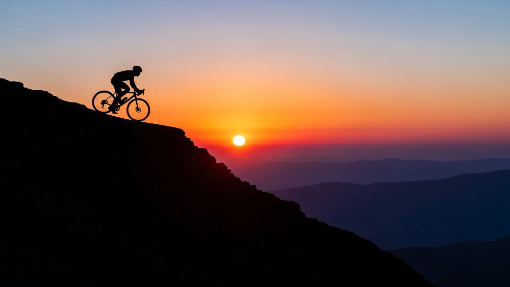 Silhouette of a cyclist on a mountain at sunset