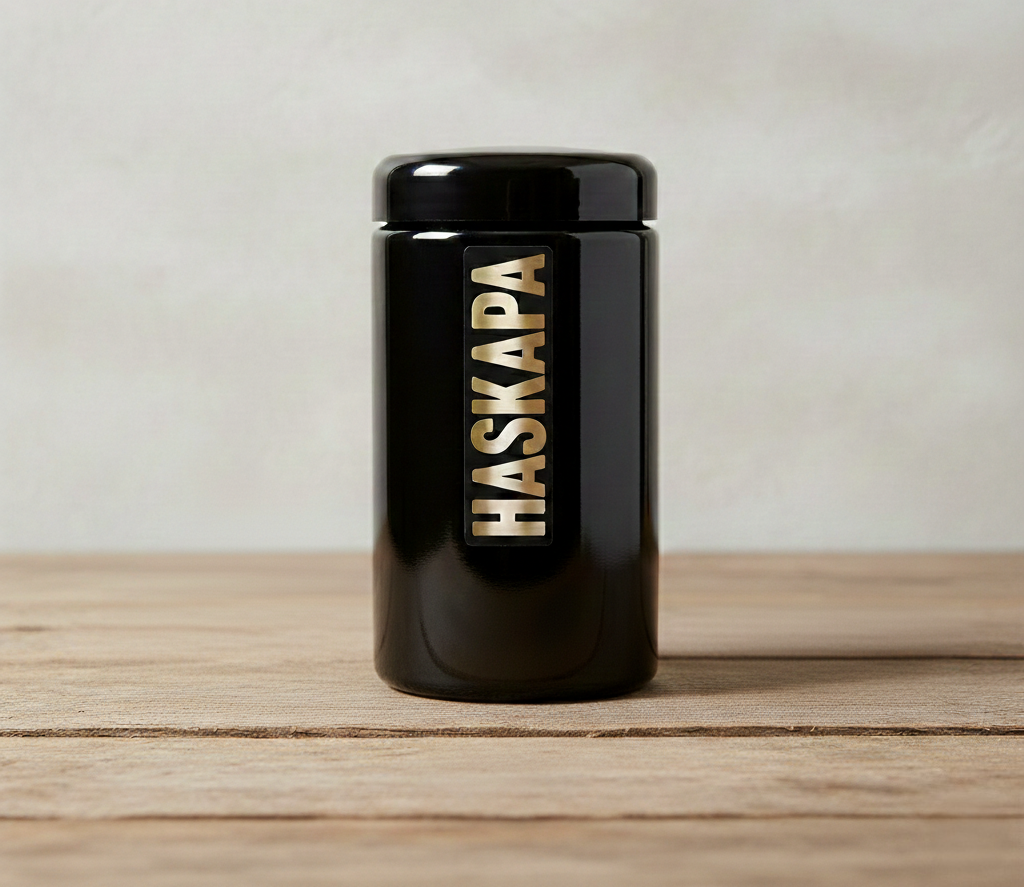 Black Haskapa container on a wooden surface with a light gray background